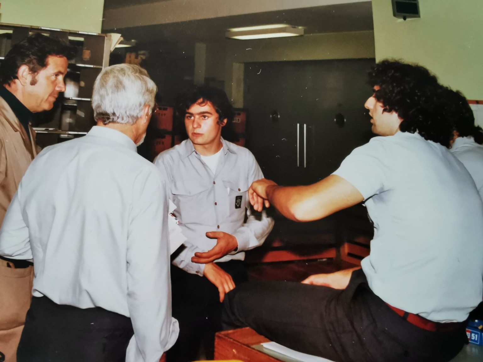 Photographie d'archive d'une conversation en groupe. Pierre-Alain Savoy se trouve au centre, à l'arrière-plan.